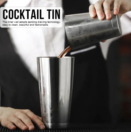 Person pouring a drink from a cocktail tin into a glass.