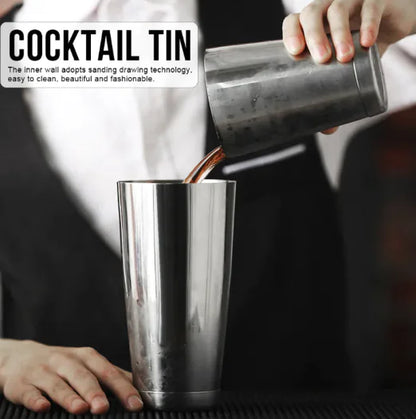 Person pouring a drink from a cocktail tin into a glass.