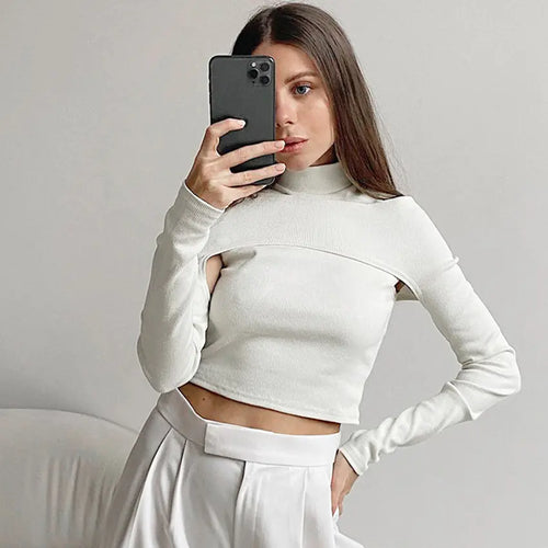 A woman wearing a white strapless t-shirt with long sleeves and a stand-up collar, paired with a white skirt.