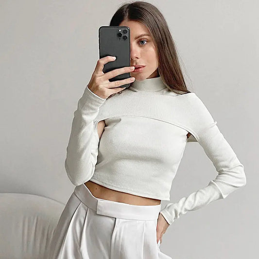A woman wearing a white strapless t-shirt with long sleeves and a stand-up collar, paired with a white skirt.